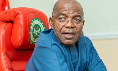 Governor Alex Otti seating on the Governor's seat with folded arms on the table, looking at camera