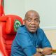 Governor Alex Otti seating on the Governor's seat with folded arms on the table, looking at camera